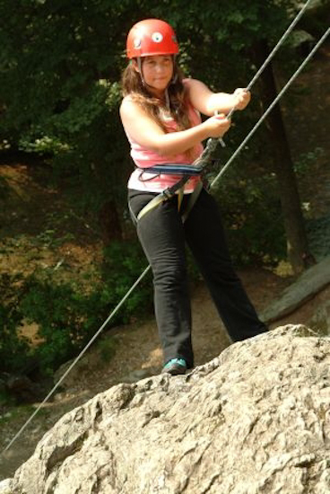 Préparation au rappel pour Marjorie. Les jambes sont tendues, les mains agrippent la corde, il n’y a plus qu’à se laisser descendre !